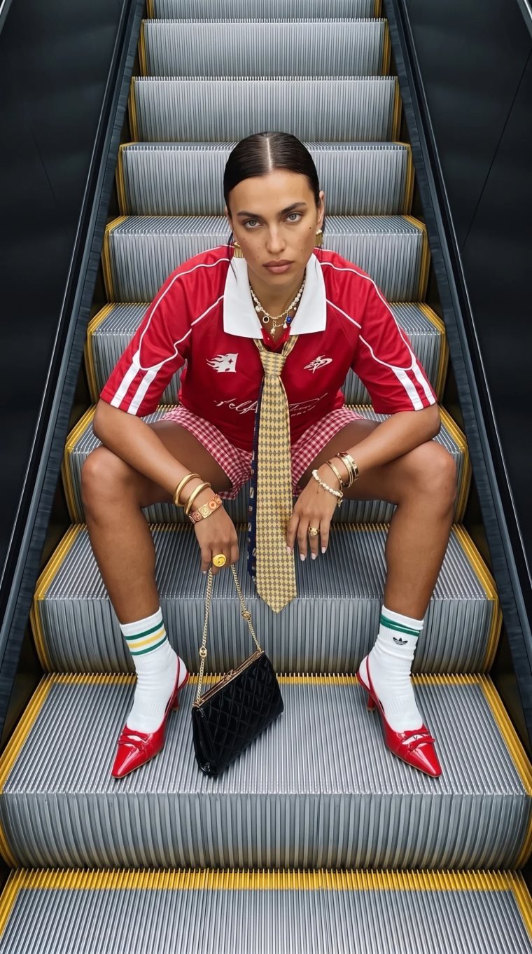 Modelo generada con IA sentada en unas escaleras mecánicas, con look deportivo